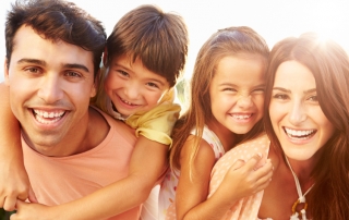 Parents Giving Children Piggyback Ride In Garden