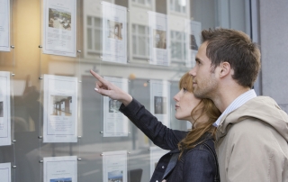Couple Looking At Display At Real Estate Office
